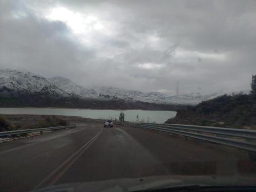 a car driving down a highway with snow covered mountains at Complejo de Cabañas Tierra de Luna in Potrerillos