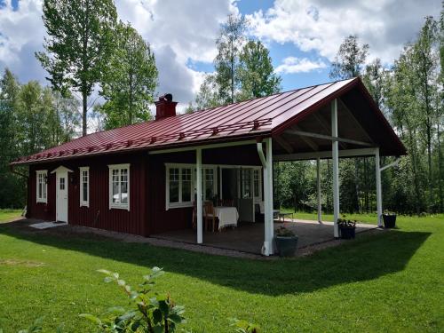 a red cabin with a porch in a yard at Nybyggd stuga i naturskönt läge in Sunne