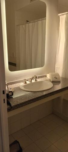 eine Badezimmerablage mit Waschbecken und Spiegel in der Unterkunft Elegance Hotel in Tres Arroyos