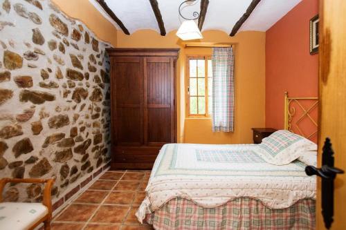 a bedroom with a bed and a stone wall at casarural lapandera in Los Villares