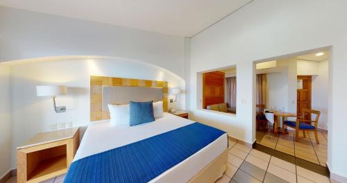a hotel room with a bed and a dining room at Park Royal Beach Huatulco - All Inclusive in Santa Cruz Huatulco