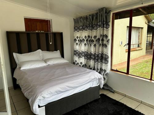 a bed in a bedroom with a window at Modest Cottage in Germiston