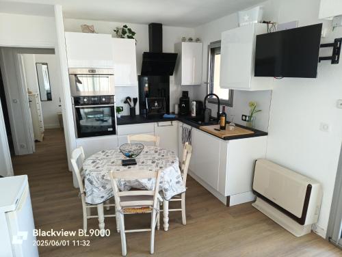 a kitchen with a table and a kitchen with white cabinets at T2 Vue latérale Mer 1 Ligne clim in Canet-en-Roussillon