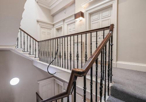 a staircase in a home with white walls and wooden railings at Cairn BNB Introduces Blythswood Apartments - Experience exceptional luxury living in Glasgow's most desirable location in Glasgow