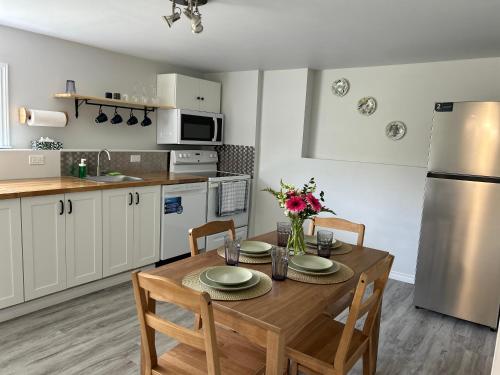 una cocina con mesa de madera con sillas y una cocina con armarios blancos. en Bridgewater downtown apartment, en Bridgewater