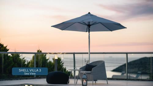 Una mesa con sombrilla y sillas en un balcón. en Seacrete villas, en La Canea