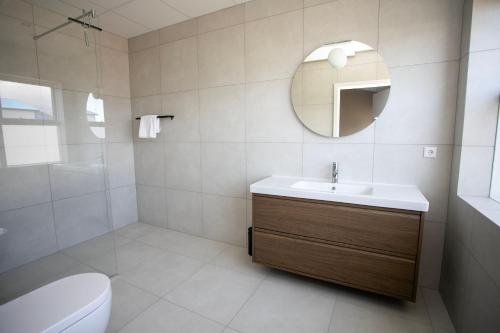 a bathroom with a sink and a mirror and a toilet at Skýjaborg Apartments in Höfn