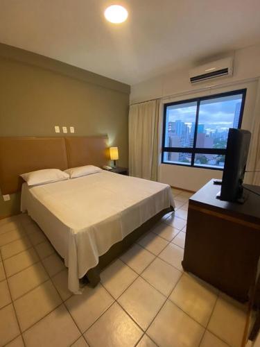 a bedroom with a bed and a television and a window at Flat no Condomínio Metrópolis - Ilha do Leite in Recife