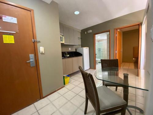 a kitchen and dining room with a glass table and chairs at Flat no Condomínio Metrópolis - Ilha do Leite in Recife