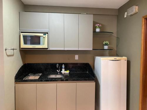 a small kitchen with a microwave and a refrigerator at Flat no Condomínio Metrópolis - Ilha do Leite in Recife
