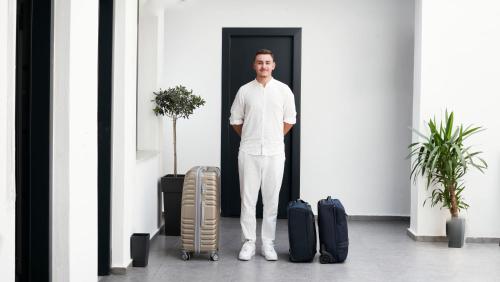 a man standing next to two pieces of luggage at Atlas Skiathos in Skiathos Town