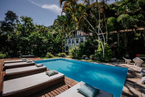 a swimming pool with lounge chairs and a resort at Pousada Picinguaba in Ubatuba