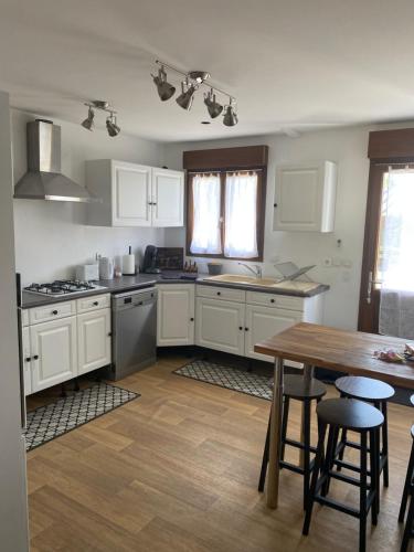 une cuisine avec des armoires blanches et une table en bois dans l'établissement Maison calme à la campagne, à Cléré-les-Pins
