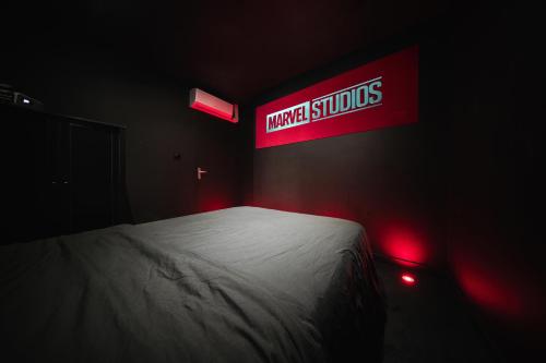 une chambre noire avec un lit avec un panneau sur le mur dans l'établissement Cinéma & Expérience 4K - Popcorn OFFERT, à Saint-Étienne