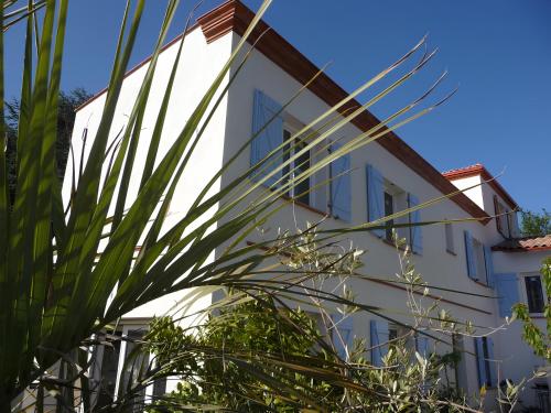 un bâtiment blanc avec des palmiers devant dans l'établissement Belle maison, beau quartier, piscine, proche centre, 5 chambres, à Toulouse
