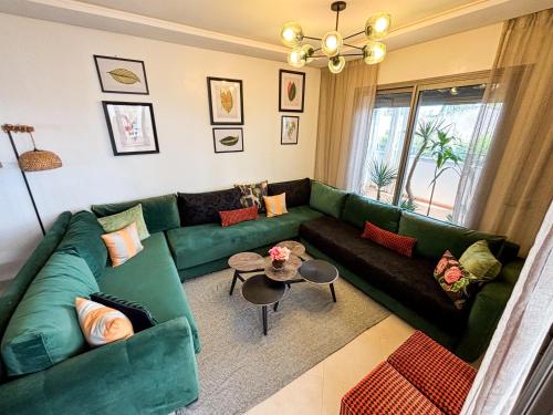 a living room with a green couch and a table at Escapade Tropicale at Jardins Cherrat in Bouznika Bay in Bouznika