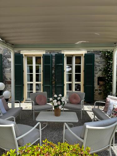 a patio with chairs and tables and green shutters at Hotel Antica Stallera in Cannobio
