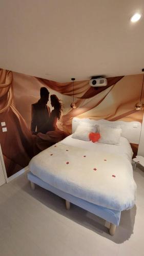 une chambre avec un lit avec un tableau sur le mur dans l'établissement les delices rooms-loveroom white, à Angers