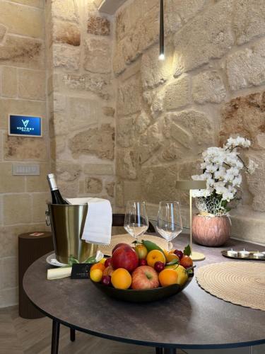 a bowl of fruit on a table with wine glasses at Victory Suite in Monopoli