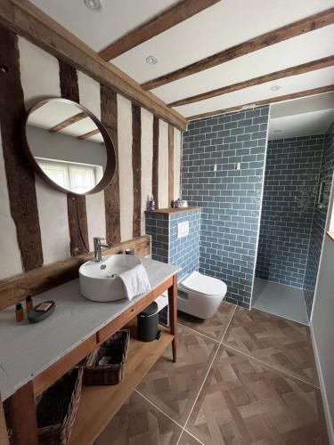 une salle de bain avec un lavabo, des toilettes et un miroir dans l'établissement La Charretrie, à Pierrefitte-en-Auge