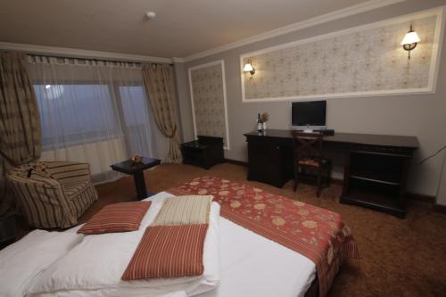 Habitación de hotel con cama y escritorio en Nobillis - Carpathian Residence en Peştera