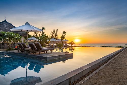 a pool at a resort with chairs and a sunset at Crown Retreat Quy Nhon Resort in Quy Nhon