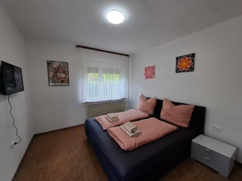 a bedroom with a bed with pink pillows on it at Ferienhaus Werratalsee in Frieda