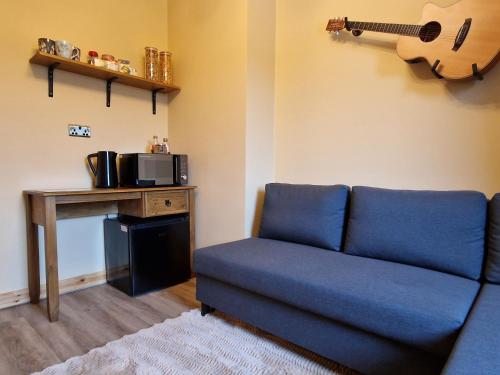 a living room with a blue couch and a guitar on the wall at Failte Stay in Inverness