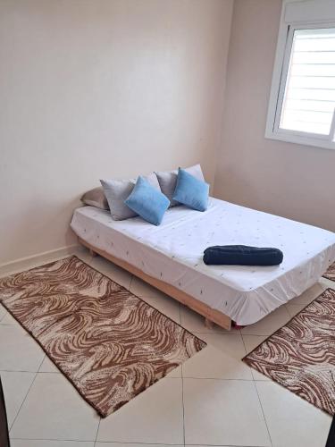 Bett in einem Zimmer mit blauen Kissen darauf in der Unterkunft اقامة Rayhana in Martil