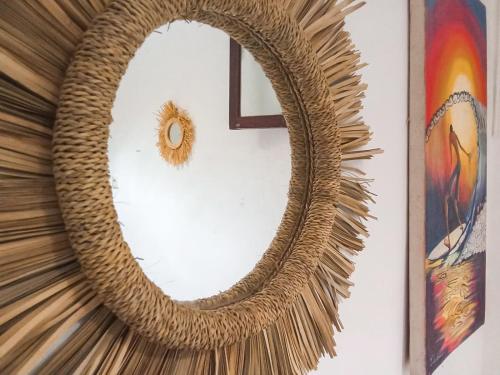 a woven wreath hanging on a wall with a mirror at Idriss Tamraght Surfhostel in Taghazout