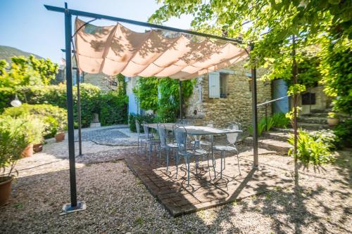 a patio with a table and chairs under an umbrella at Le Refuge Provençal Nijonyas in Malaucène