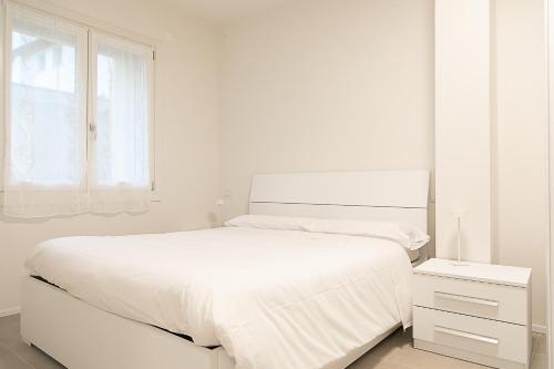 a white bedroom with a white bed and a window at Ca Borsa III - Suite nel cuore di Treviso in Treviso