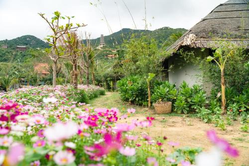 a garden with pink flowers in front of a building at Crown Retreat Quy Nhon Resort in Quy Nhon