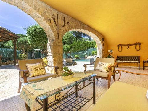 eine Terrasse mit 2 Stühlen, einem Tisch und einem Torbogen in der Unterkunft Holiday Home Mas Ambros by Interhome in Calonge