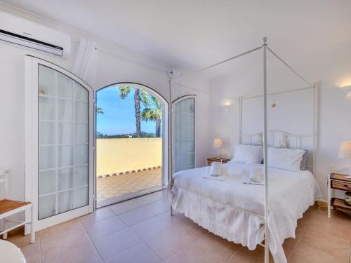 a white bedroom with a bed and a view of a beach at Villa Villa Monte da Torre by Interhome in Loulé