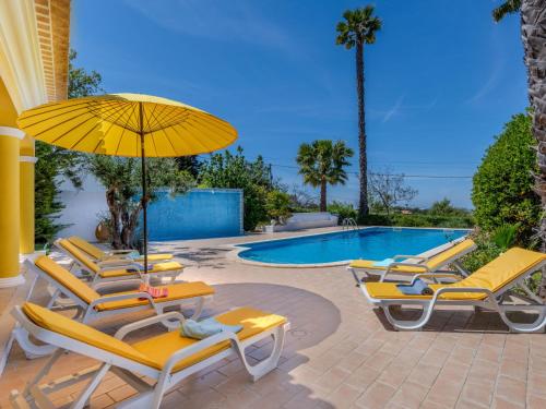 a group of chairs and an umbrella next to a pool at Villa Villa Monte da Torre by Interhome in Loulé