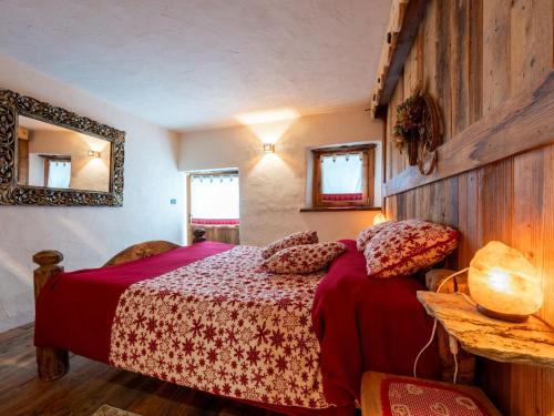 a bedroom with a bed with a red comforter at Apartment Baita Baulin-1 by Interhome in Baulen