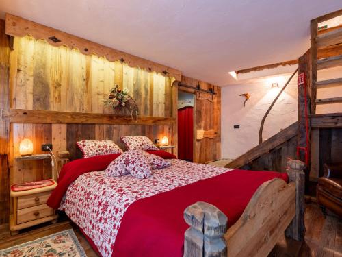 a bedroom with a red bed with wooden walls at Apartment Baita Baulin-1 by Interhome in Baulen