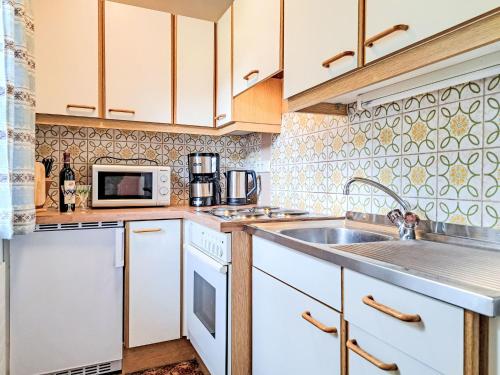 kuchnia z białymi szafkami, zlewem i kuchenką mikrofalową w obiekcie Apartment Fichtenblick App- 3 by Interhome w mieście Auffach
