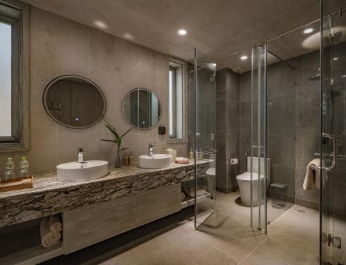a bathroom with two sinks and a shower at Crown Retreat Quy Nhon Resort in Quy Nhon