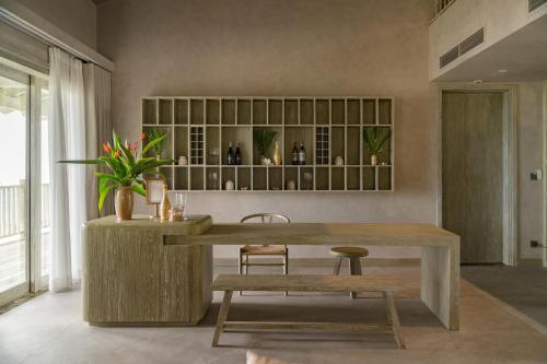 a dining room with a wooden table and a bench at Crown Retreat Quy Nhon Resort in Quy Nhon