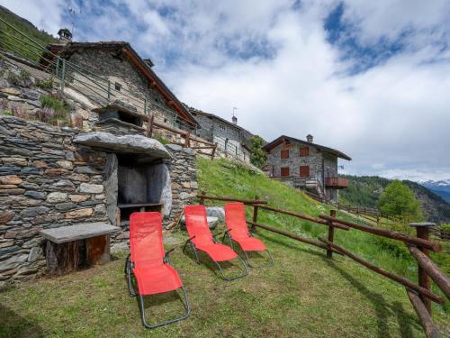 a group of red chairs sitting in front of a building at Apartment Baita Baulin-2 by Interhome in Baulen