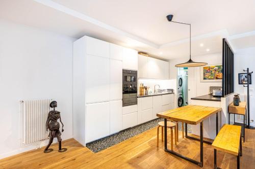 une cuisine avec des armoires blanches et une table en bois dans l'établissement GuestReady - Chic & spacious living in Madeleine, à Paris
