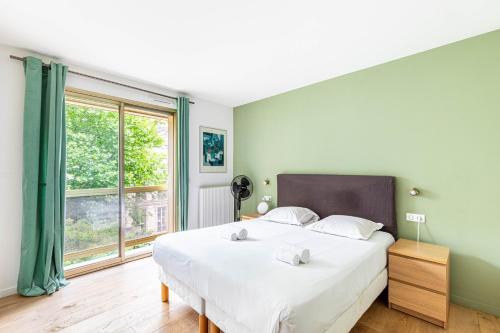 une chambre avec un grand lit et une grande fenêtre dans l'établissement GuestReady - Chic & spacious living in Madeleine, à Paris