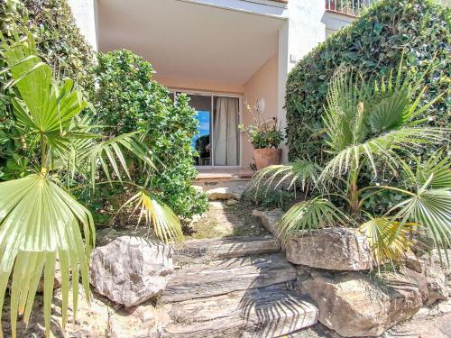 un jardin avec des palmiers et des rochers devant une maison dans l'établissement Apartment Les Rivages de Coudoulière-8 by Interhome, à Six-Fours-les-Plages