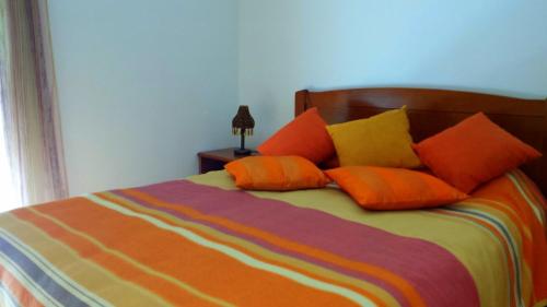 Una cama con almohadas de color naranja y amarillo. en Casa Feliz, en Odeceixe