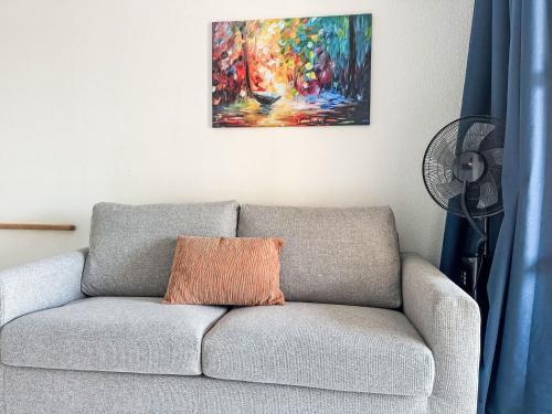 un canapé avec un oreiller orange assis sous un tableau dans l'établissement Studio Le Village - C1201 by Interhome, à Agay