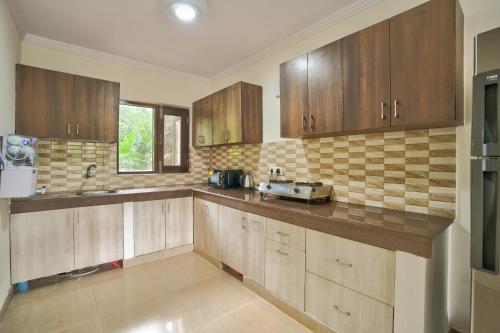 a large kitchen with wooden cabinets and a sink at Luxury 3BHK Villa With Private Pool in Candolim in Nerul