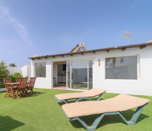 a patio with two picnic tables and chairs on a lawn at Loft en zona rural de Lanzarote in Conil