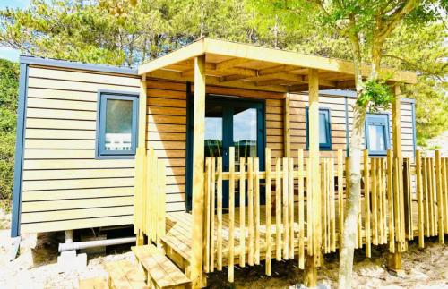 une petite cabane en bois avec un porche sur la plage dans l'établissement Camping Cristal d'Opale, à Camiers